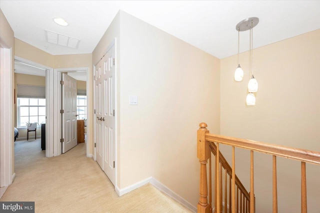 corridor with an upstairs landing, light colored carpet, and baseboards