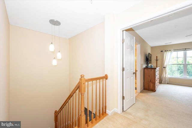 corridor with an upstairs landing, carpet, and baseboards