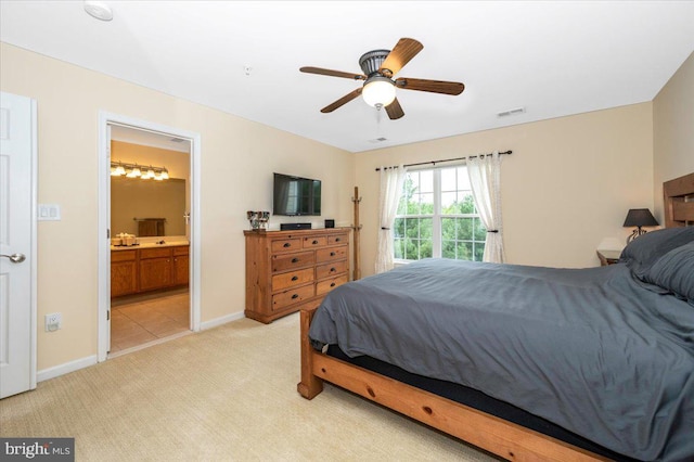 bedroom with light carpet, baseboards, connected bathroom, and a ceiling fan