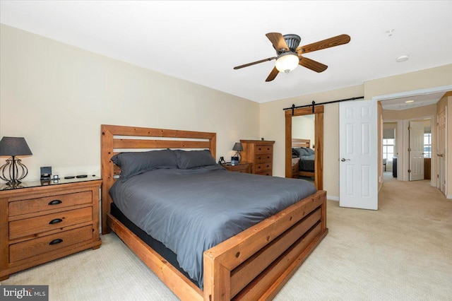 bedroom featuring light carpet, a ceiling fan, and a barn door