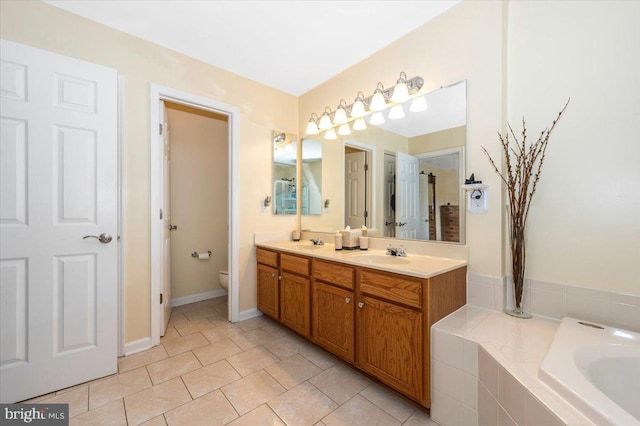 bathroom featuring toilet, double vanity, tiled tub, and tile patterned floors