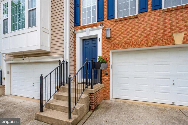 entrance to property with a garage, brick siding, and concrete driveway