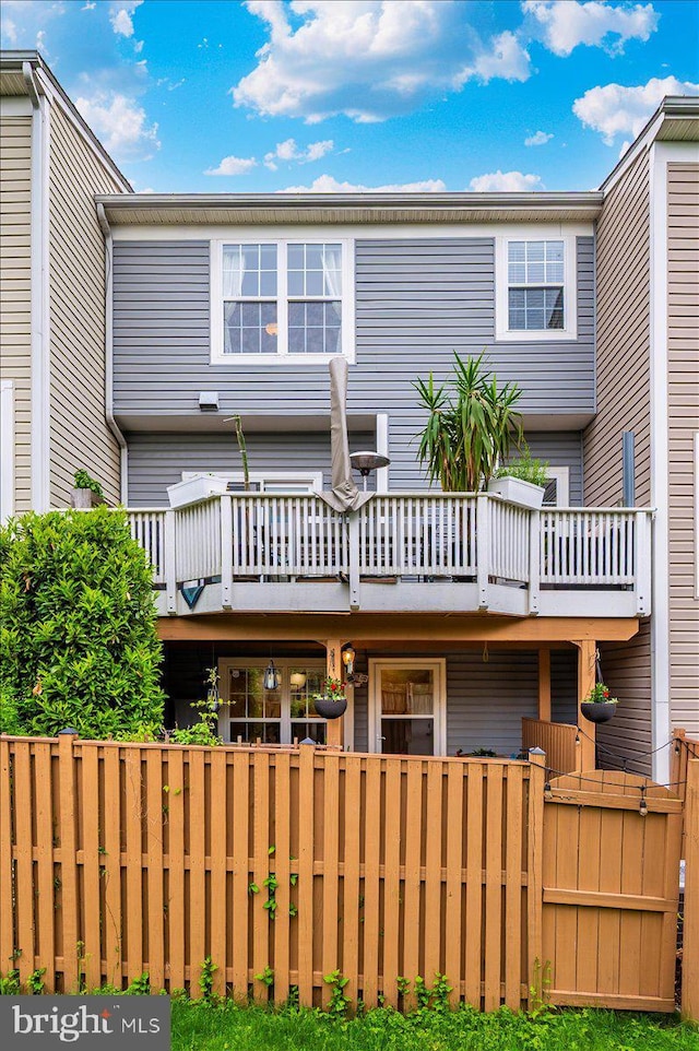 back of property with fence and a wooden deck