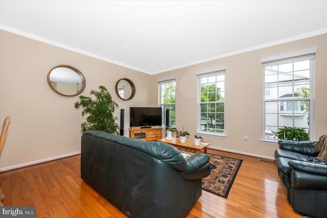 living area with light wood-style floors, crown molding, and baseboards