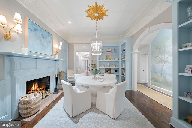 109 Duke St, Alexandria, VA 22314 - dining room with ornamental molding, built in shelves, wood finished floors, a chandelier, and a warm lit fireplace