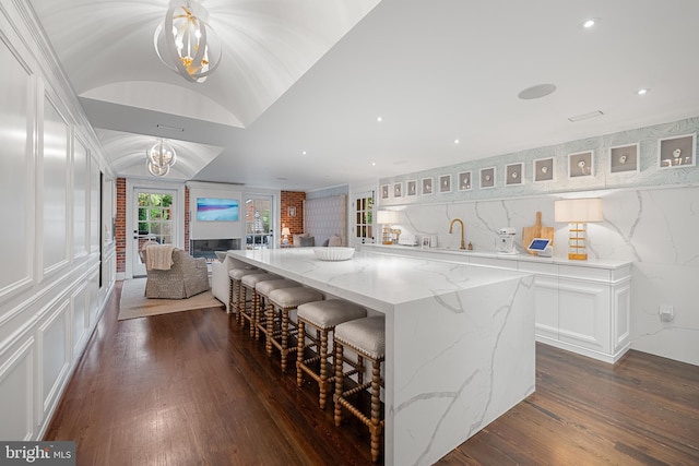 109 Duke St, Alexandria, VA 22314 - kitchen featuring dark wood-type flooring, white cabinets, a kitchen bar, open floor plan, and lofted ceiling