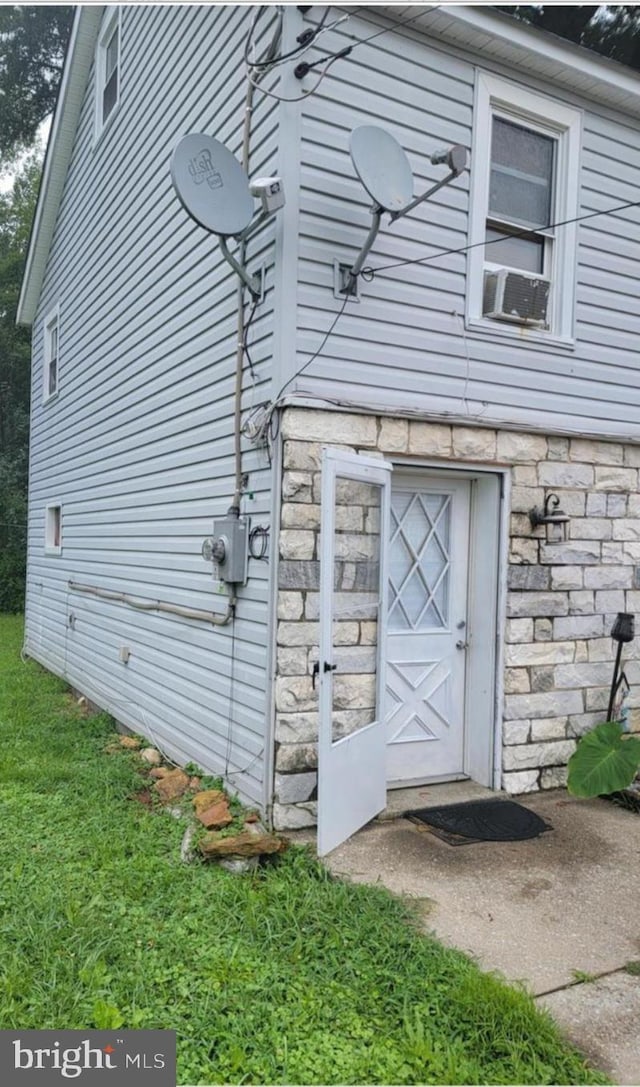 view of property exterior featuring stone siding and cooling unit