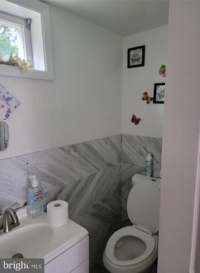 half bath featuring a sink, toilet, and tile walls