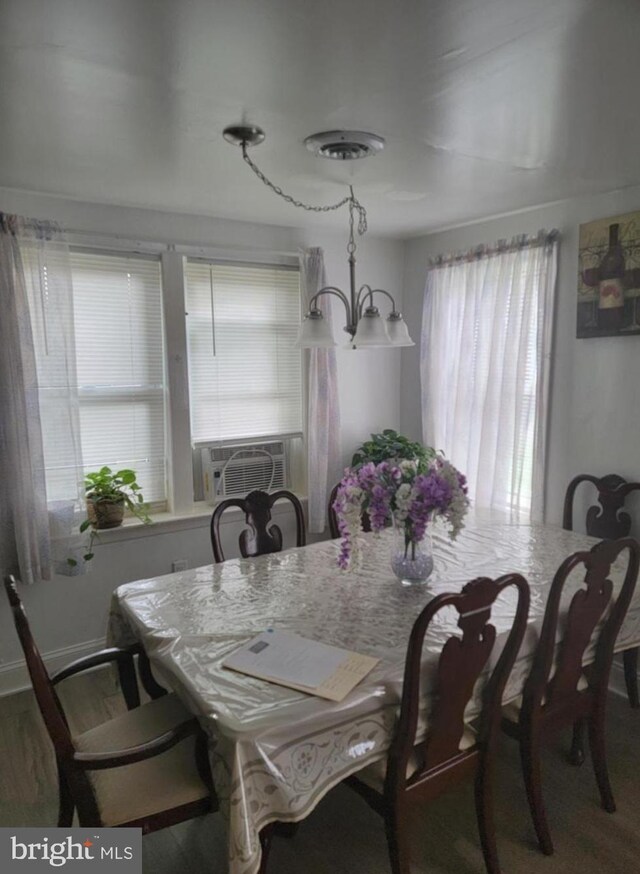 dining area featuring an inviting chandelier, wood finished floors, a healthy amount of sunlight, and cooling unit