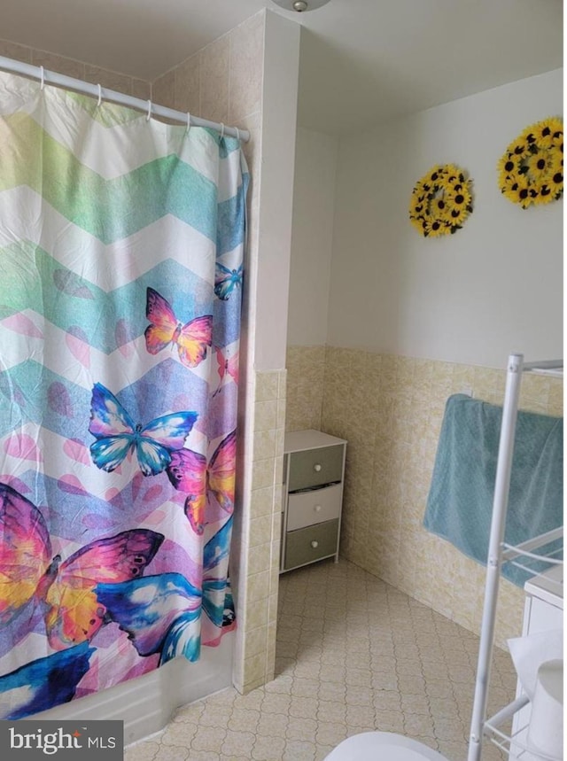 full bathroom featuring tile walls, a wainscoted wall, and curtained shower