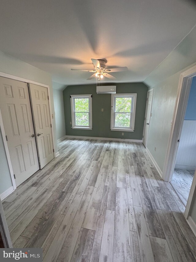 2117 Kearny St NE, Washington, DC 20018 - unfurnished living room featuring a wall mounted air conditioner, ceiling fan, wood-type flooring, baseboards, and vaulted ceiling