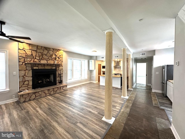 2117 Kearny St NE, Washington, DC 20018 - unfurnished living room with decorative columns, a stone fireplace, baseboards, and dark wood-style flooring