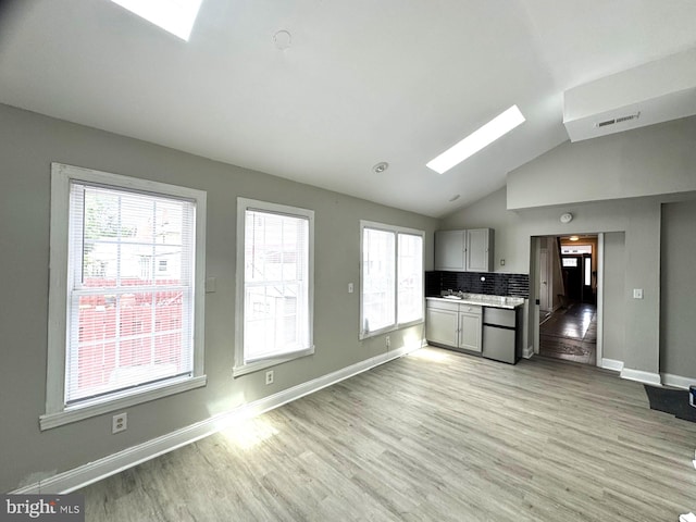 2117 Kearny St NE, Washington, DC 20018 - kitchen featuring a skylight, light wood finished floors, refrigerator, lofted ceiling, and backsplash