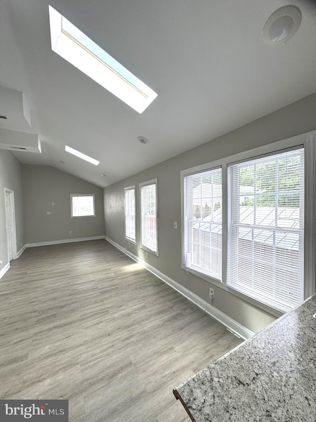 2117 Kearny St NE, Washington, DC 20018 - unfurnished living room featuring a skylight, vaulted ceiling, wood finished floors, and baseboards