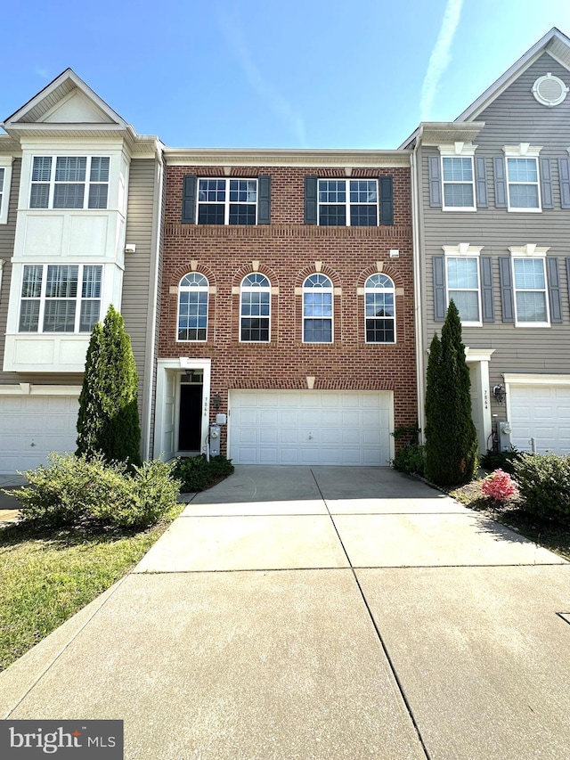 multi unit property with an attached garage, driveway, and brick siding