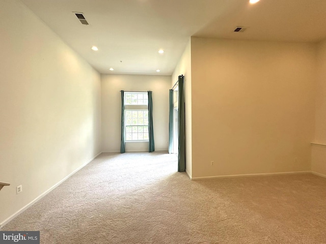 empty room with light colored carpet, recessed lighting, and baseboards