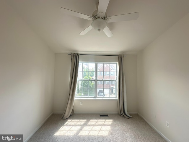 carpeted spare room featuring ceiling fan and baseboards