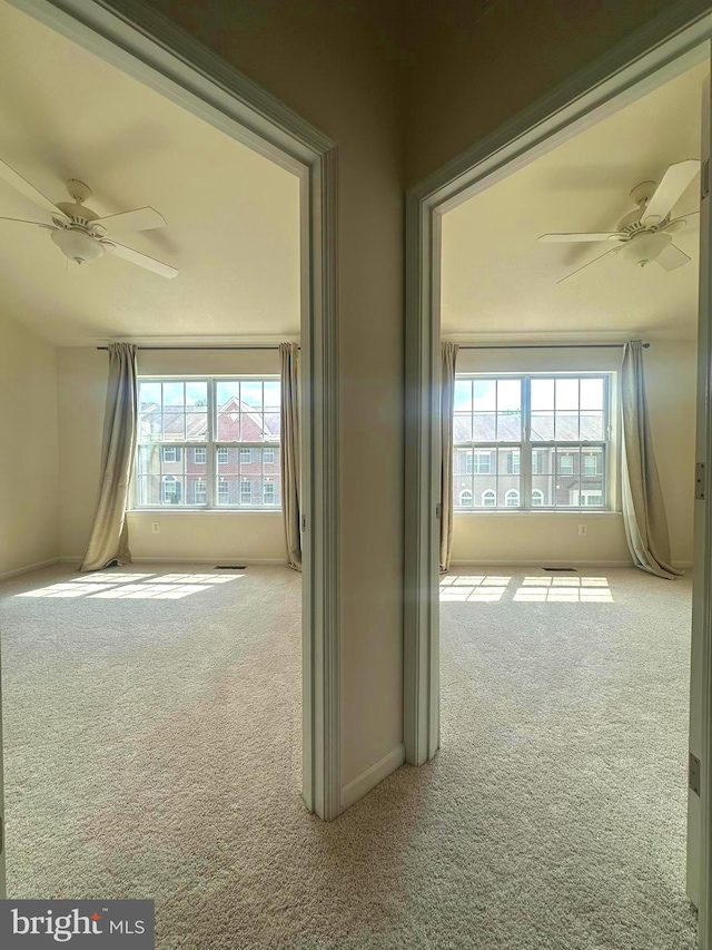 carpeted spare room featuring ceiling fan, healthy amount of natural light, and baseboards