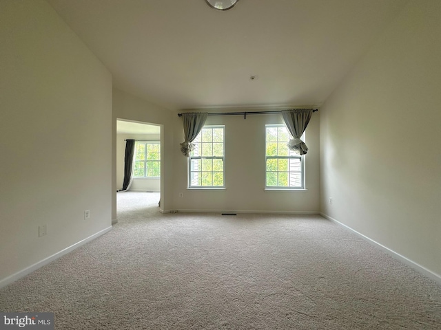 carpeted empty room featuring healthy amount of natural light and baseboards