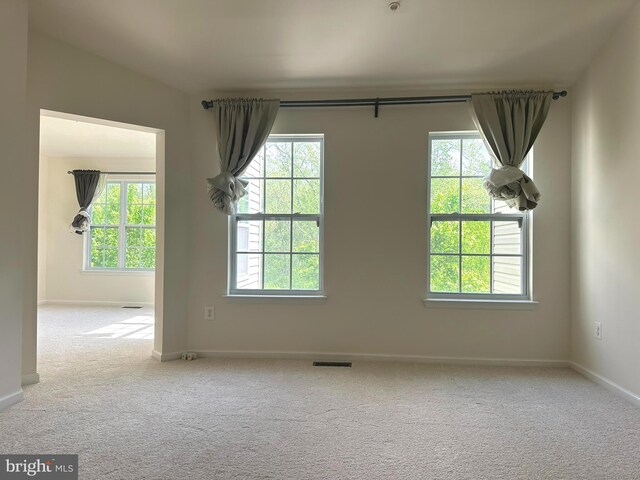 carpeted empty room featuring plenty of natural light and baseboards