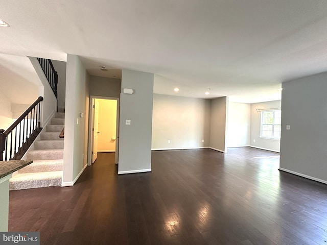 unfurnished living room featuring dark wood finished floors, stairway, recessed lighting, and baseboards