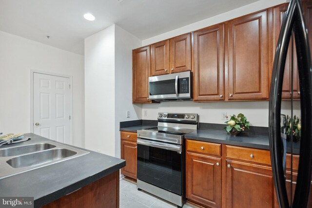 24764 Stone Station Ter, Aldie, VA 20105 - kitchen with stainless steel appliances, dark countertops, a sink, light tile patterned floors, and brown cabinets