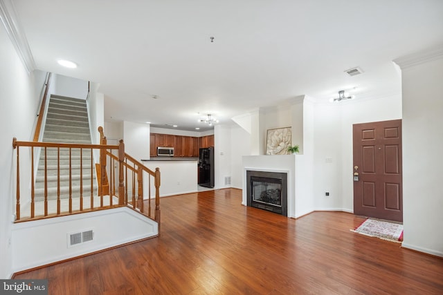 24764 Stone Station Ter, Aldie, VA 20105 - unfurnished living room with stairs, crown molding, wood finished floors, a glass covered fireplace, and baseboards