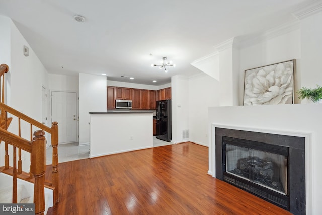 24764 Stone Station Ter, Aldie, VA 20105 - unfurnished living room featuring a glass covered fireplace, stairway, ornamental molding, wood finished floors, and a chandelier