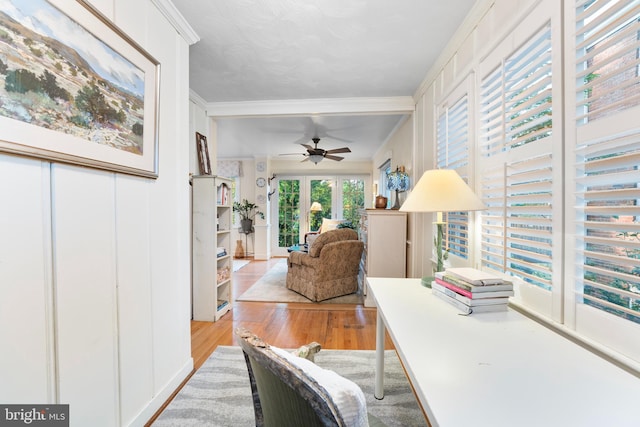 home office with light wood finished floors, a ceiling fan, and ornamental molding