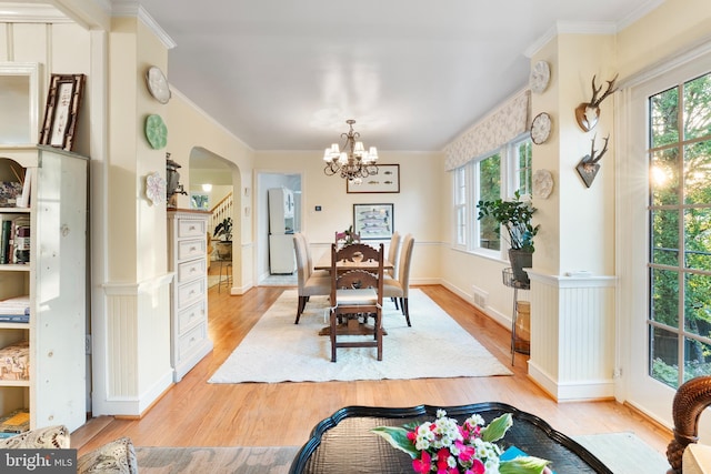 dining space featuring a wealth of natural light, a chandelier, light wood-style flooring, and arched walkways