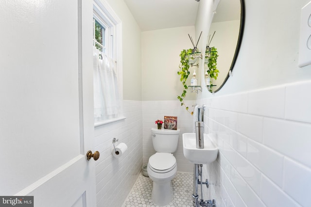 bathroom with tile patterned flooring, toilet, tile walls, and a wainscoted wall