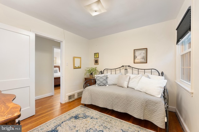bedroom featuring baseboards, visible vents, and wood finished floors