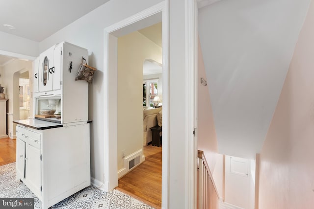 hallway featuring arched walkways, visible vents, and light wood-style floors