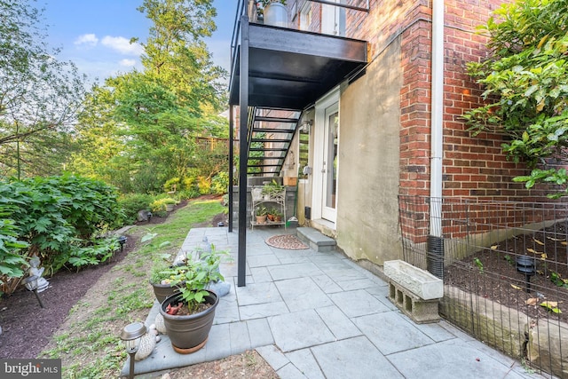 exterior space featuring brick siding, stairway, and a patio