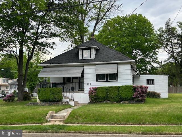 bungalow-style home with a shingled roof and a front lawn