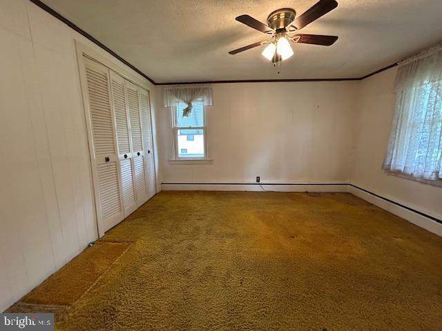 unfurnished bedroom with crown molding, carpet flooring, ceiling fan, and a closet