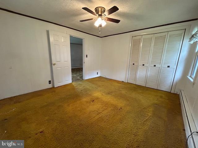 unfurnished bedroom featuring a closet, a baseboard radiator, a ceiling fan, and carpet flooring
