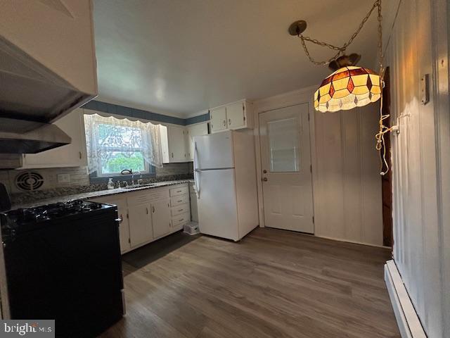 kitchen featuring a sink, baseboard heating, dark wood finished floors, freestanding refrigerator, and black gas stove
