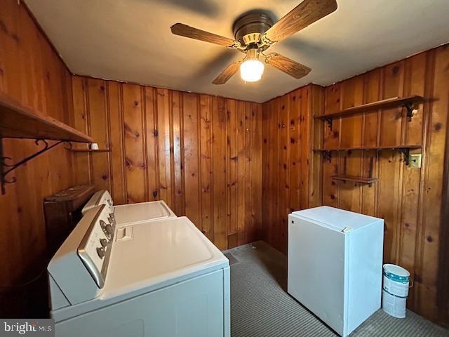 washroom with laundry area, washer and clothes dryer, and wood walls