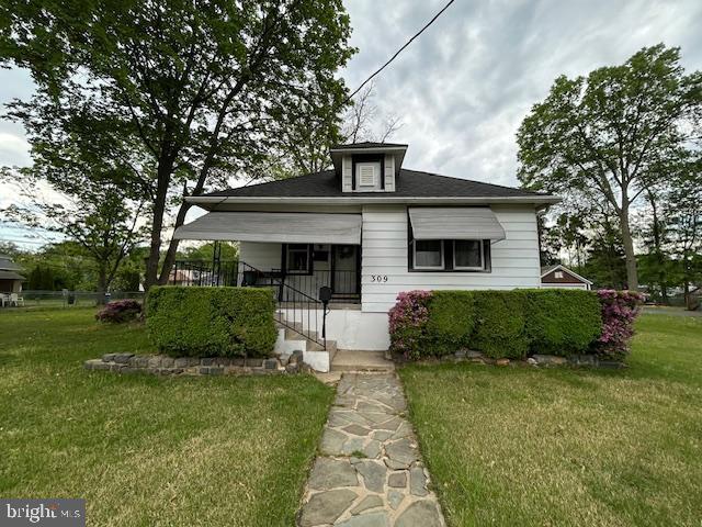 bungalow-style home featuring covered porch and a front yard