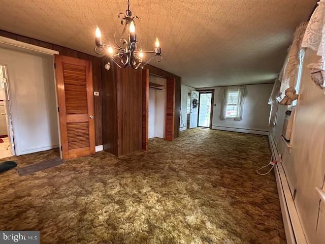 unfurnished dining area with a baseboard heating unit, a textured ceiling, an inviting chandelier, and carpet