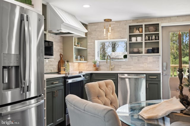 kitchen with decorative backsplash, appliances with stainless steel finishes, open shelves, a sink, and light countertops