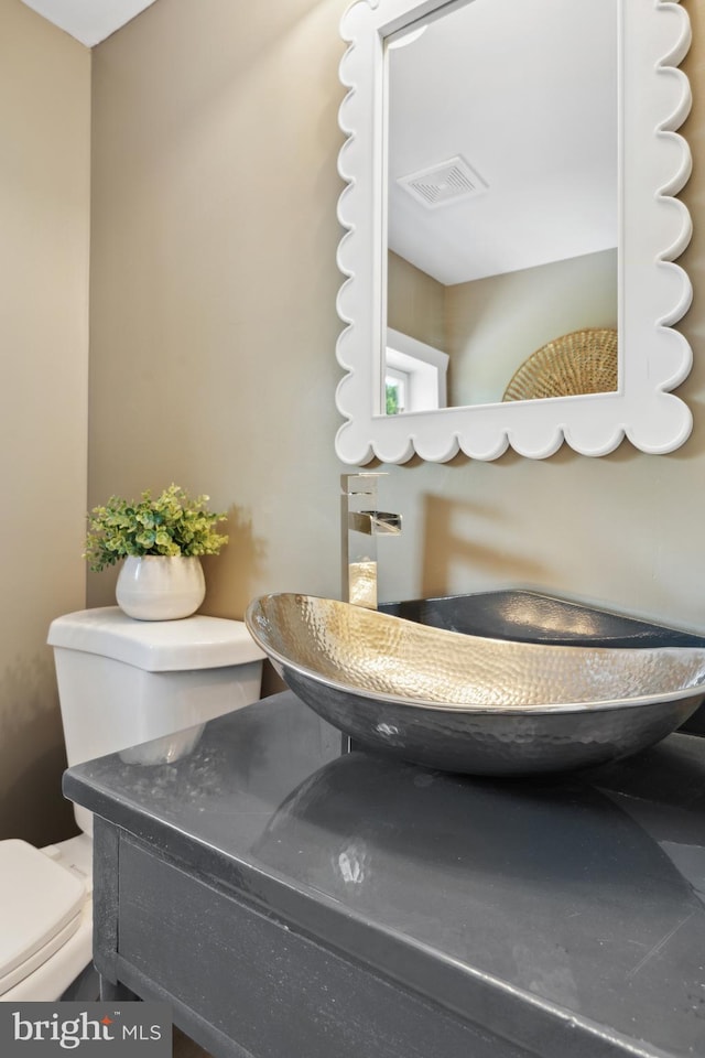 bathroom featuring toilet, visible vents, and a sink