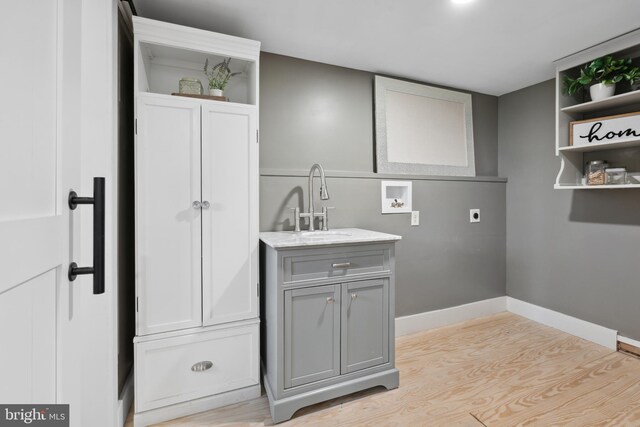 clothes washing area with hookup for a washing machine, light wood-type flooring, a sink, cabinet space, and hookup for an electric dryer