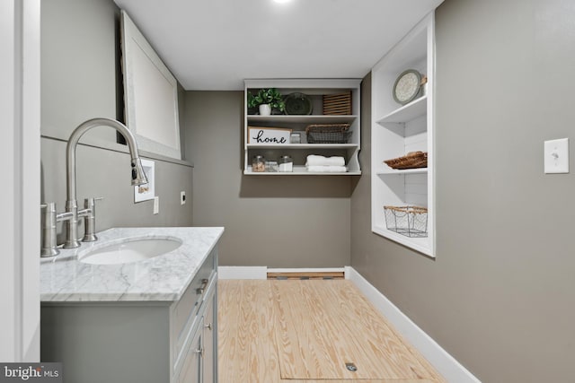 bathroom featuring vanity, baseboards, and wood finished floors