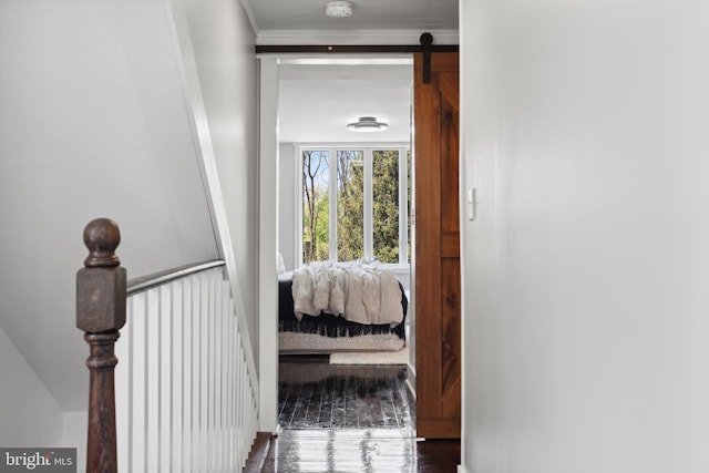 corridor with a barn door, crown molding, and wood finished floors