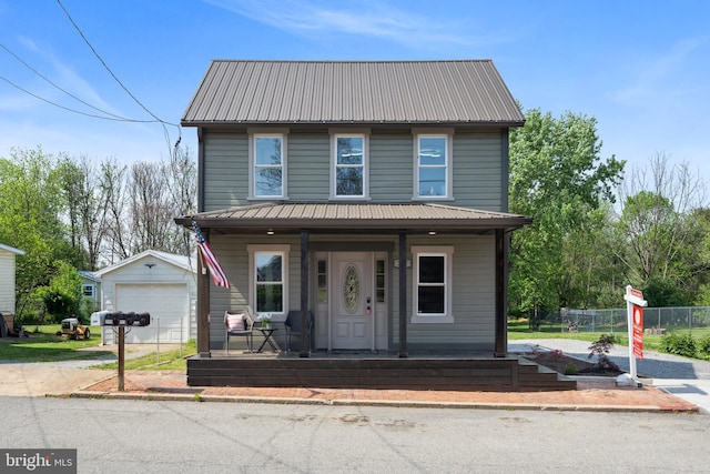 view of front of property featuring a garage, covered porch, an outdoor structure, and metal roof