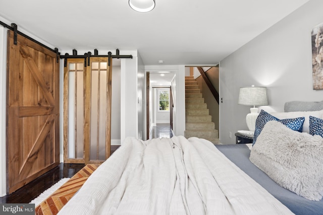 bedroom featuring a barn door and wood finished floors
