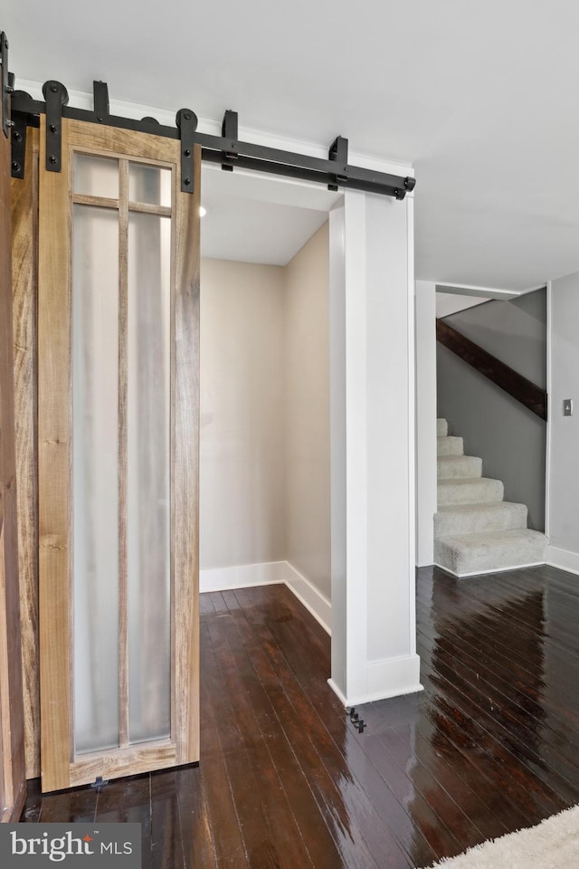 interior space with stairway, baseboards, a barn door, and hardwood / wood-style flooring