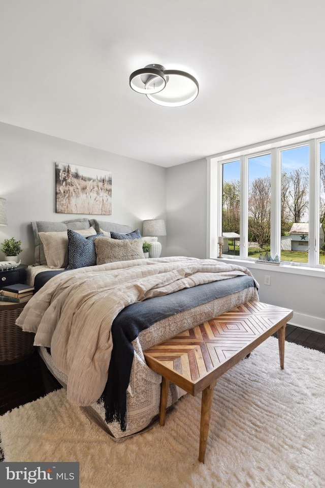 bedroom with baseboards, wood finished floors, and multiple windows
